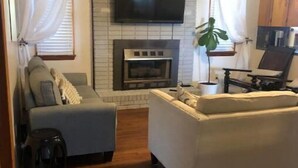 Ein Wohnzimmer mit Kamin, Fernseher und einer Couch.