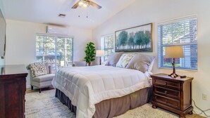 Un dormitorio con una cama grande, un aparador, una silla y una ventana con persianas.