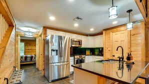 Une cuisine compacte dotée d’un îlot central, d’appareils électroménagers en acier inoxydable et d’éléments décoratifs en bois.
