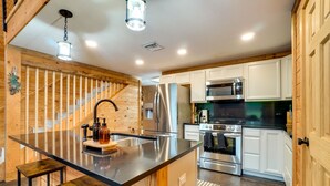 Une cuisine moderne dotée d’un îlot central, d’appareils électroménagers en acier inoxydable et d’éléments décoratifs en bois.