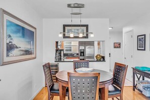 Un espace repas comprenant une table ronde, des chaises, un lustre et des œuvres d’art encadrées accrochées aux murs.