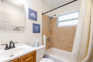 Un bagno con lavandino bianco, toilette, vasca da bagno e doccia.