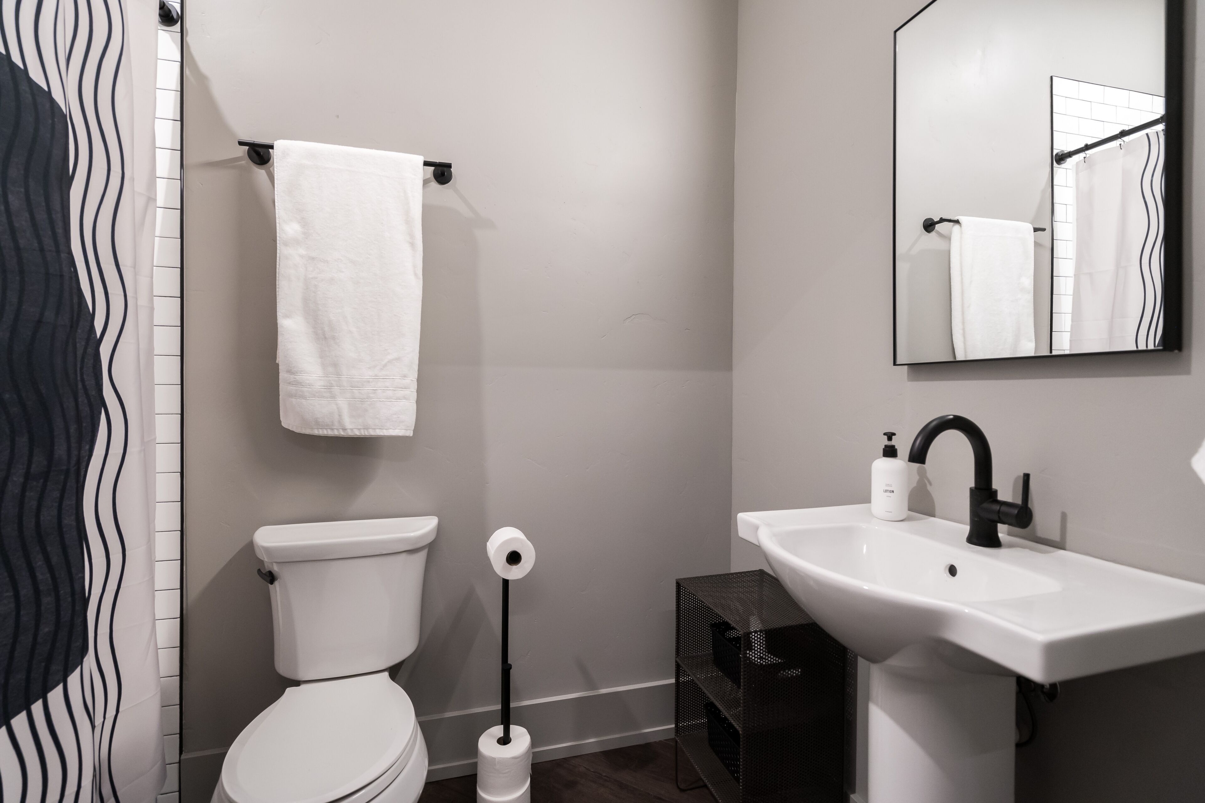 A modern bathroom with a toilet, sink, and mirror.
