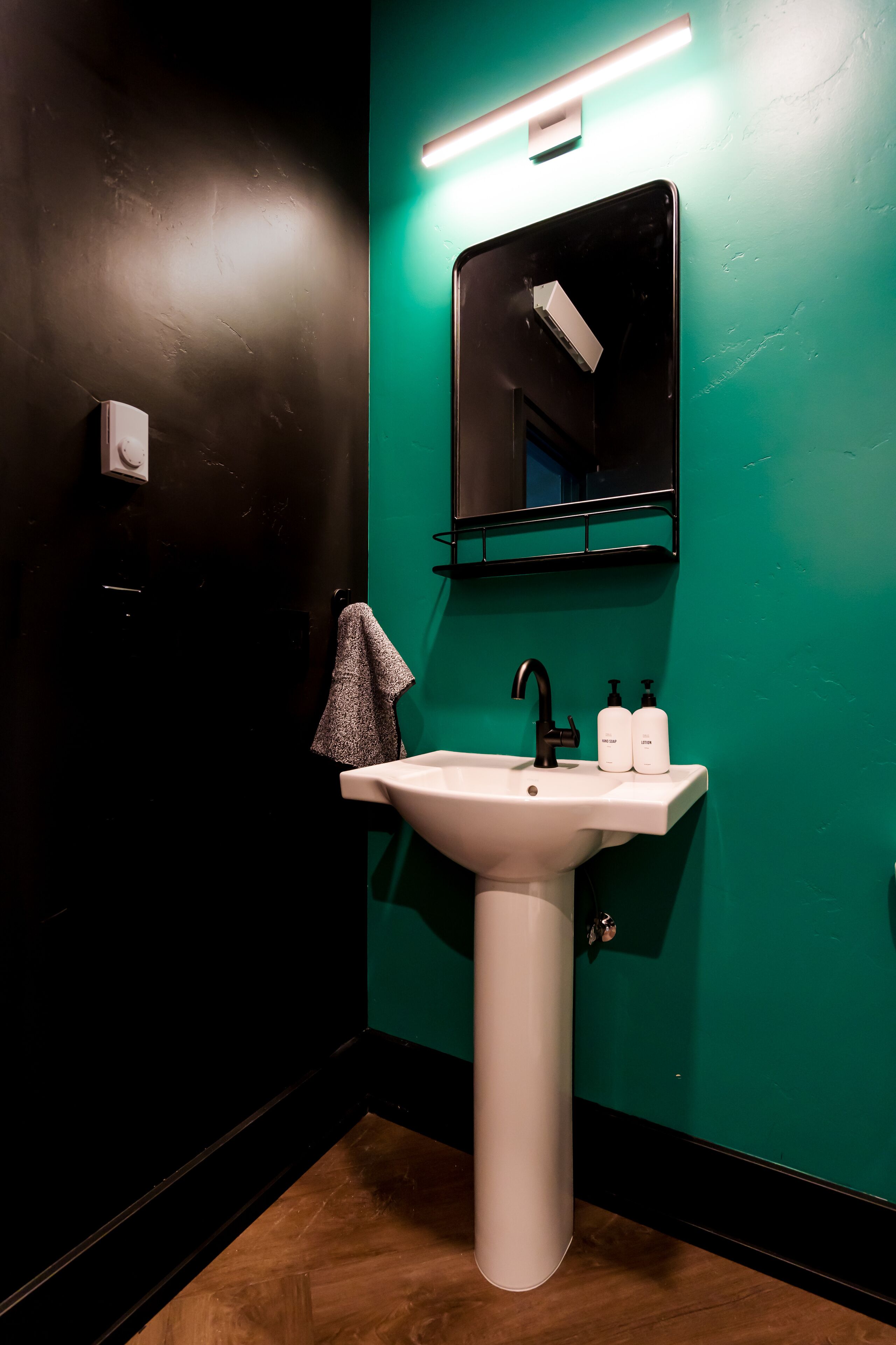 A bathroom with a white sink, a mirror, and two bottles of hand soap.