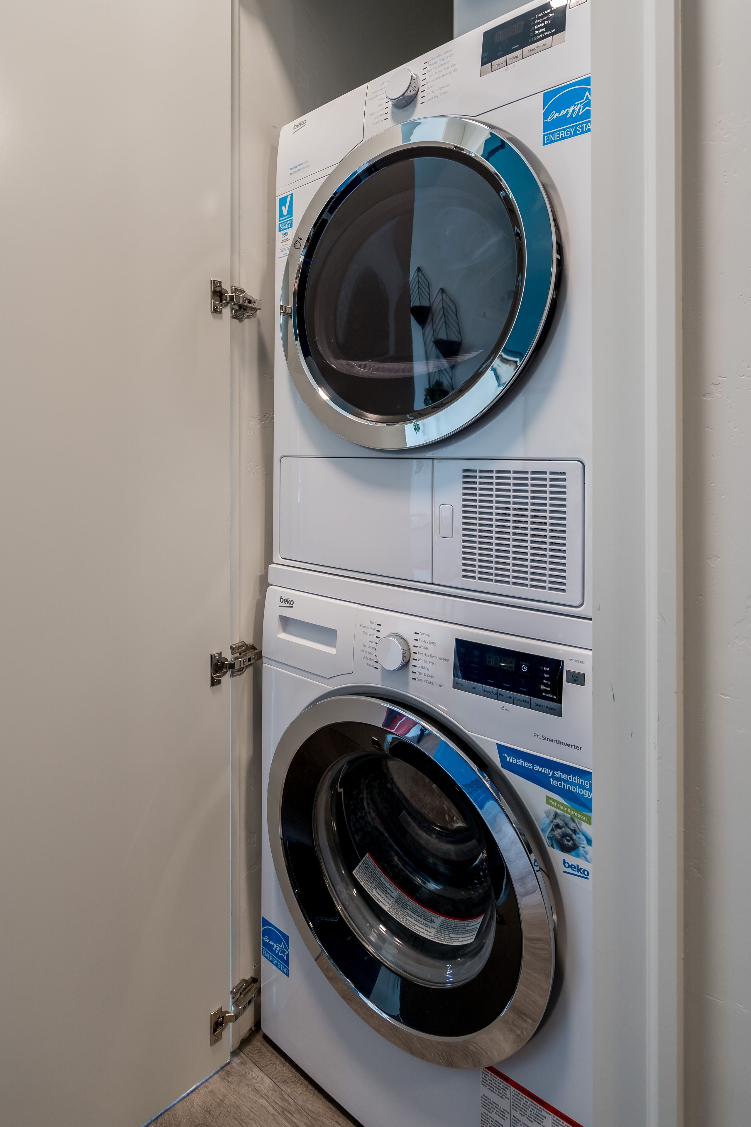 Un appareil combiné lave-linge et sèche-linge, de type « empilable », doté d’un panneau de commande et d’une porte.