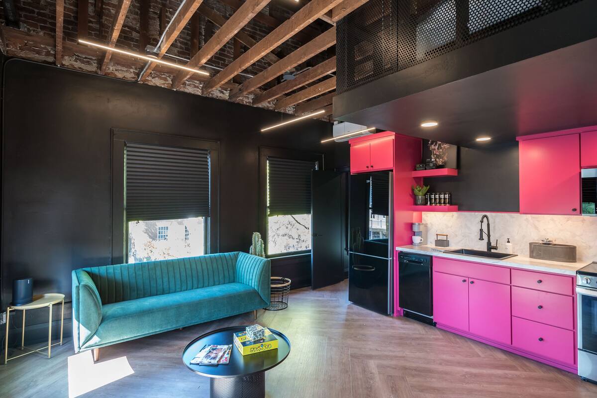 A modern kitchen with pink cabinets, a black refrigerator, and a sink.