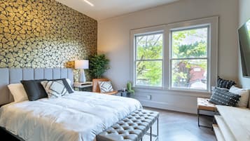 Relax in this serene bedroom with a large bed, tufted headboard, and a comfortable bench at its foot.