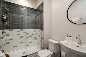 A modern bathroom with a glass-enclosed shower, a white toilet, and a sink with toiletries. - The 505 Eugene (Eugene)