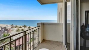 A balcony with a view of the beach and palm trees.