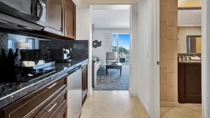 A modern kitchen with dark wooden cabinets, a black countertop, and a built-in microwave.