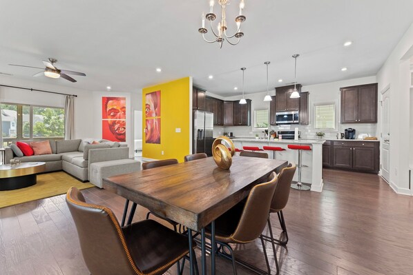 A modern kitchen with dark wood cabinets, a central island, and a dining area with a wooden table and chairs.