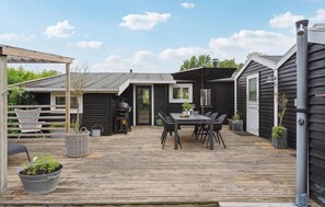 En träaltan med ett bord och stolar, en grill och en pergola.
