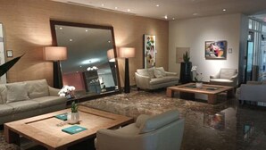 Un moderno vestíbulo de hotel con un espejo grande, dos sofás, una mesa de centro y una planta en maceta.
