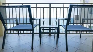 Ein Balkon mit zwei Stühlen und einem kleinen Tisch, mit Blick auf ein Gewässer.