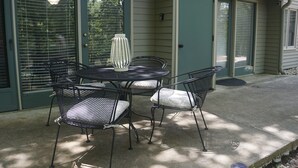 A patio with a round table and four chairs, a decorative vase, and a door with a window.