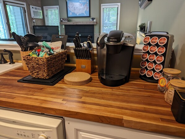 Un plan de travail de cuisine avec une machine à café Keurig, un panier de collations, un bloc à couteaux et un support à dosettes de café.