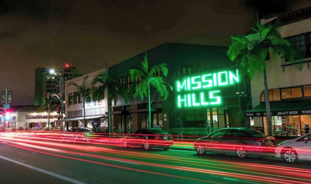 Un edificio con un letrero de neón que dice 'MISSION HILLS' de noche.