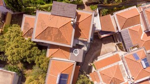 An aerial view of a residential area with multiple houses featuring red-tiled roofs and some with solar panels. - Mirto 4 Apartment (Santa Maria Navarrese)