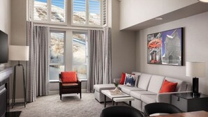 Une chambre d’hôtel moderne dotée d’une grande fenêtre, d’un canapé, d’une table à manger et d’un téléviseur.