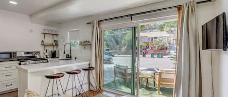 A modern kitchen with a central island, bar stools, and a dining area with a glass table and chairs.