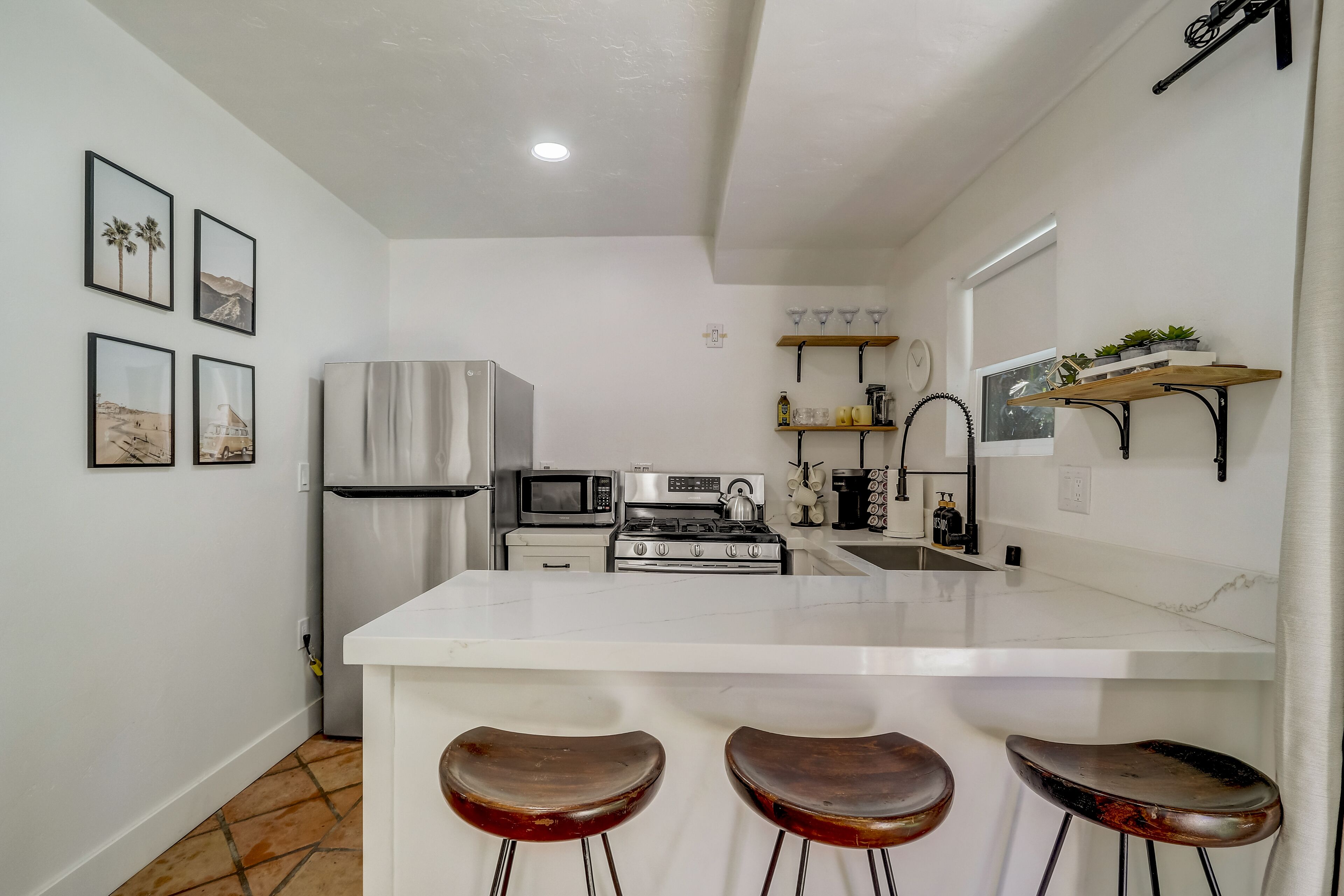 A modern kitchen with a central island, bar stools, stainless steel appliances, and decorative wall art.
