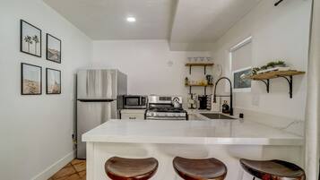 A modern kitchen with a central island, bar stools, stainless steel appliances, and decorative wall art.