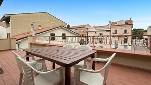 Eine Terrasse mit Tisch und Stühlen und Blick auf umliegende Gebäude, der Himmel ist wolkenlos.