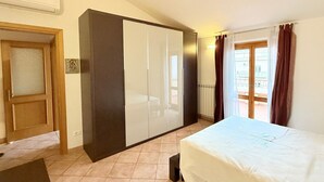 Ein Schlafzimmer mit Bett, Kleiderschrank und Blick ins Freie.