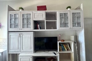 A room with a white cabinet with multiple compartments, a television, and a shelf with books. - SE010 - Senigallia, one bedroom apartment on the sea with beach (Senigallia)