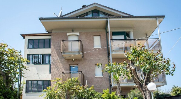 A multi-story residential building with balconies, windows, and a clear sky.