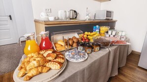 A breakfast buffet with croissants, fruits, and beverages.