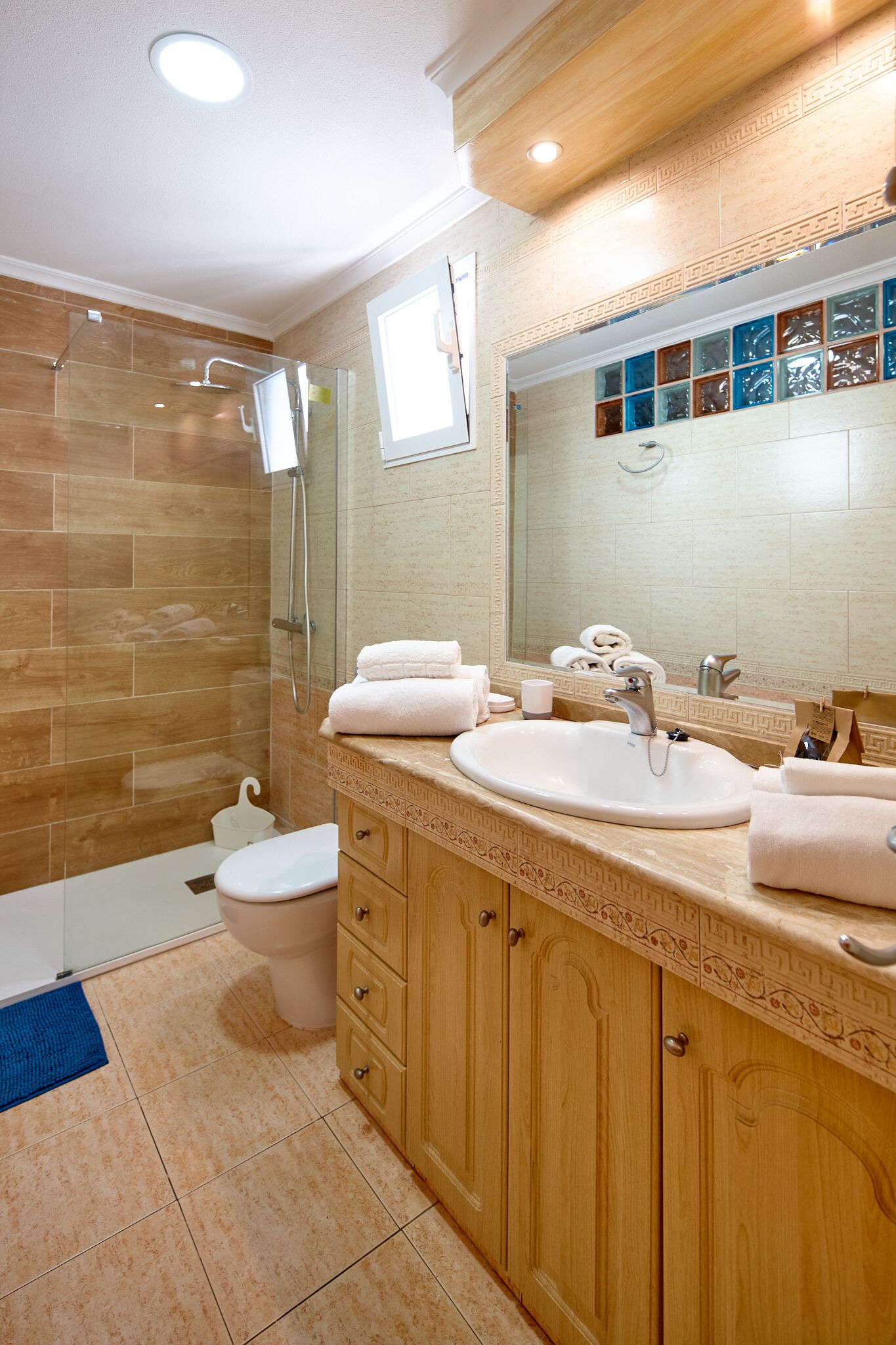 A modern bathroom with a glass shower enclosure, a white sink, and a large mirror.