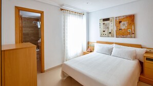 Ein Schlafzimmer mit einem großen Bett, einem Holzkopfstück, Nachttischen, einem Kleiderschrank und einer Duschkabine.