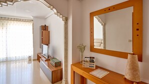 Ein Hotelzimmer mit einem Holzkonsolentisch, einem großen Spiegel, einer Blumenvase und einem Holzkasten.