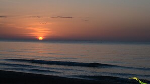 Ein Sonnenuntergang über einem ruhigen Meer mit sanften Wellen.