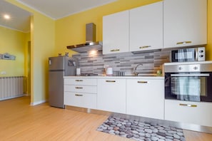 A modern kitchen with white cabinets, stainless steel appliances, and a tiled backsplash.