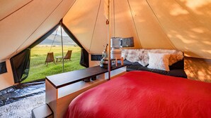 A tent with a bed, a table, and chairs. - Glamping Tibet Tent #1 (Whitehall)