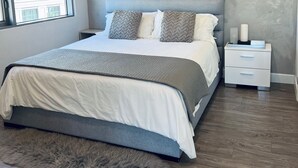 Un dormitorio moderno con una cama grande, una mesita de noche y una ventana con persianas.