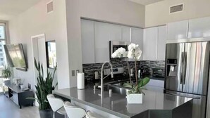 Una cocina moderna con una isla central, electrodomésticos de acero inoxidable y taburetes de bar.