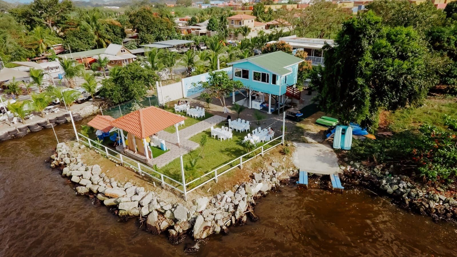 Une maison sur pilotis, construite au-dessus d’une rivière, avec un espace salon extérieur et une piscine.