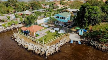 Une maison sur pilotis, construite au-dessus d’une rivière, avec un espace salon extérieur et une piscine.