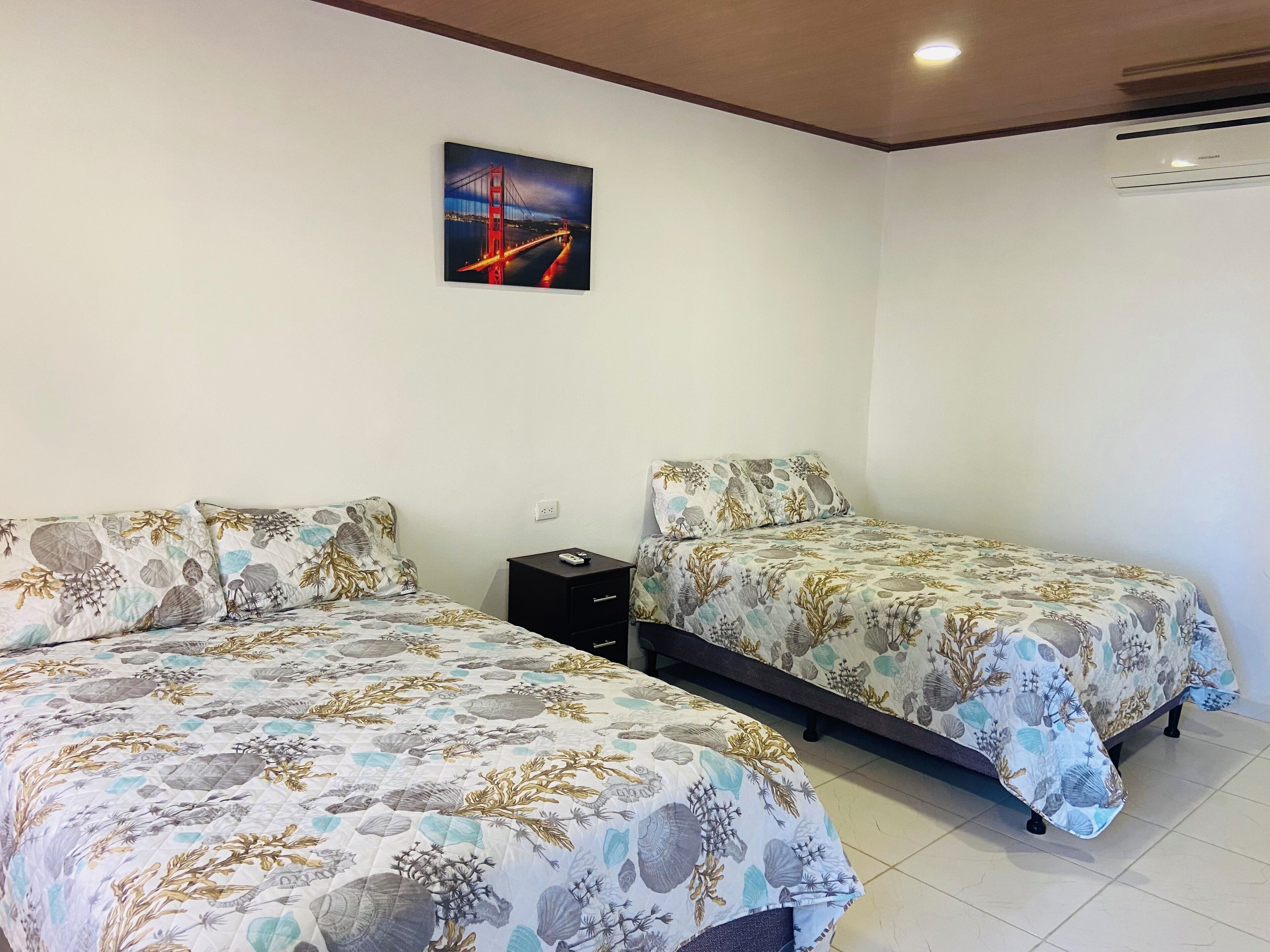 Una habitación de hotel con dos camas, una mesita de noche y un cuadro de un puente.