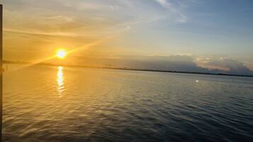 A sunset over a calm body of water with a distant shoreline.
