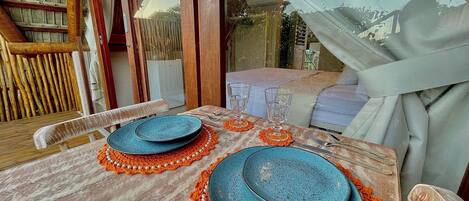 A dining table set with blue plates, orange placemats, and clear glassware.