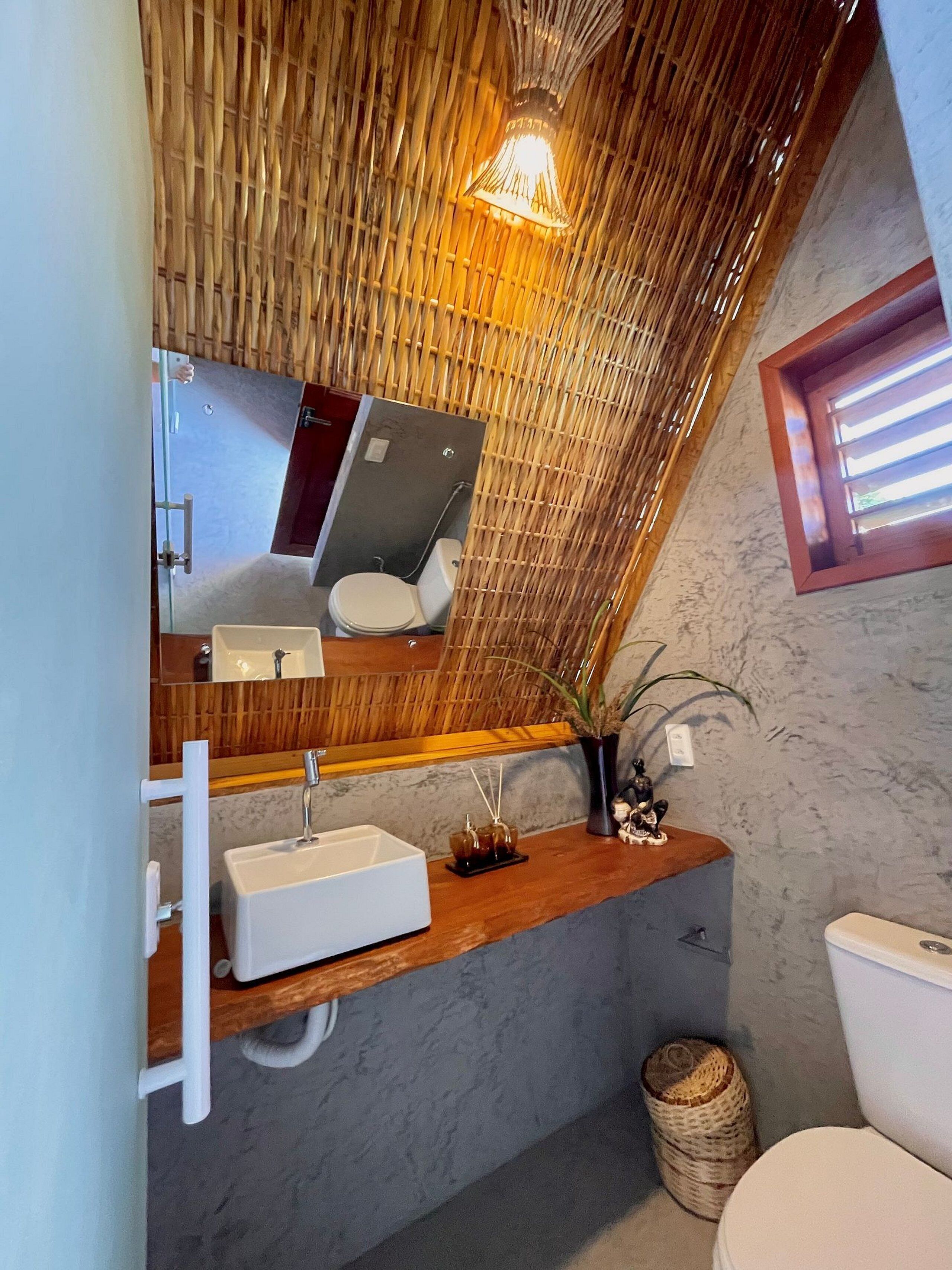 A bathroom with a wooden ceiling, a white sink, a mirror, and a toilet.