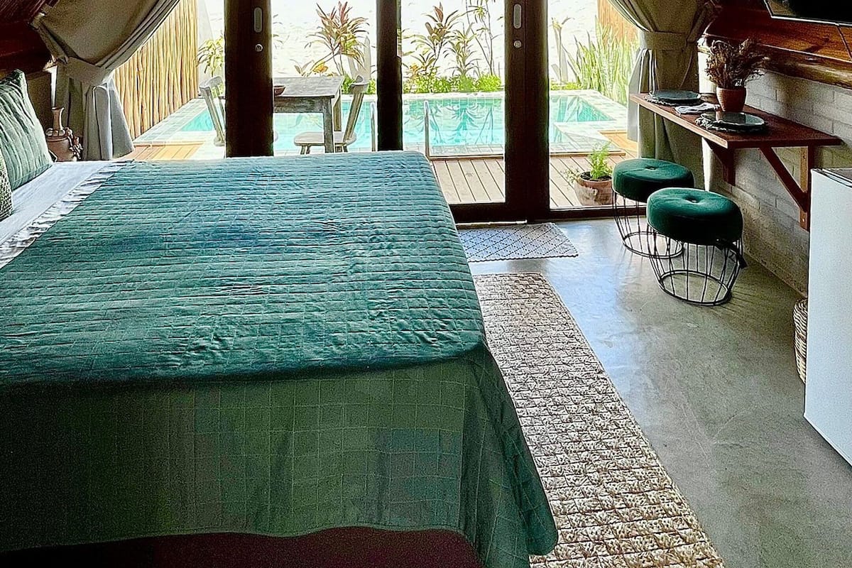 A spacious attic bedroom with a large bed, a dining area, and a view of the outdoors.
