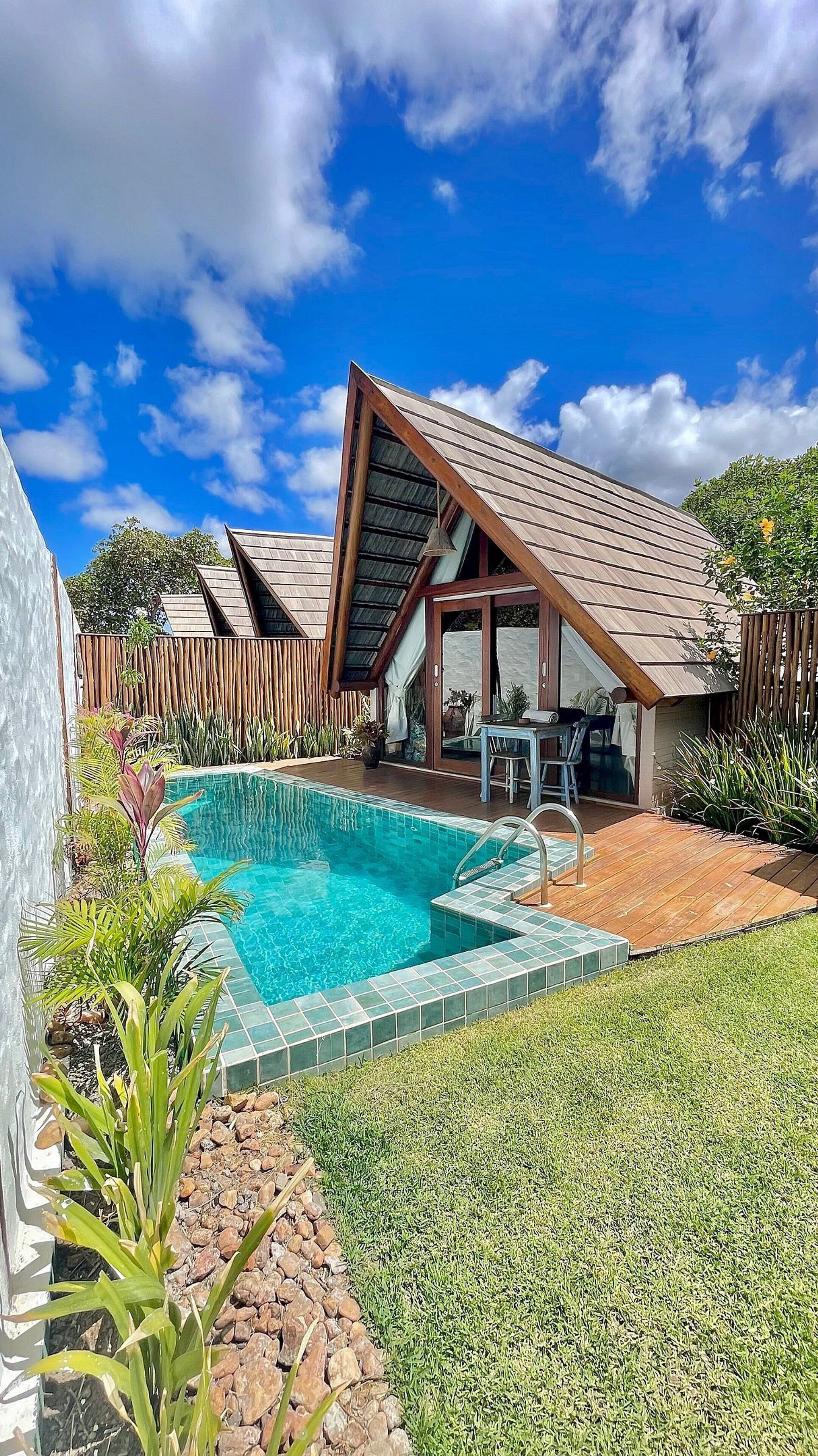 Una casa moderna con piscina, un patio cubierto y un jardín trasero cercado.