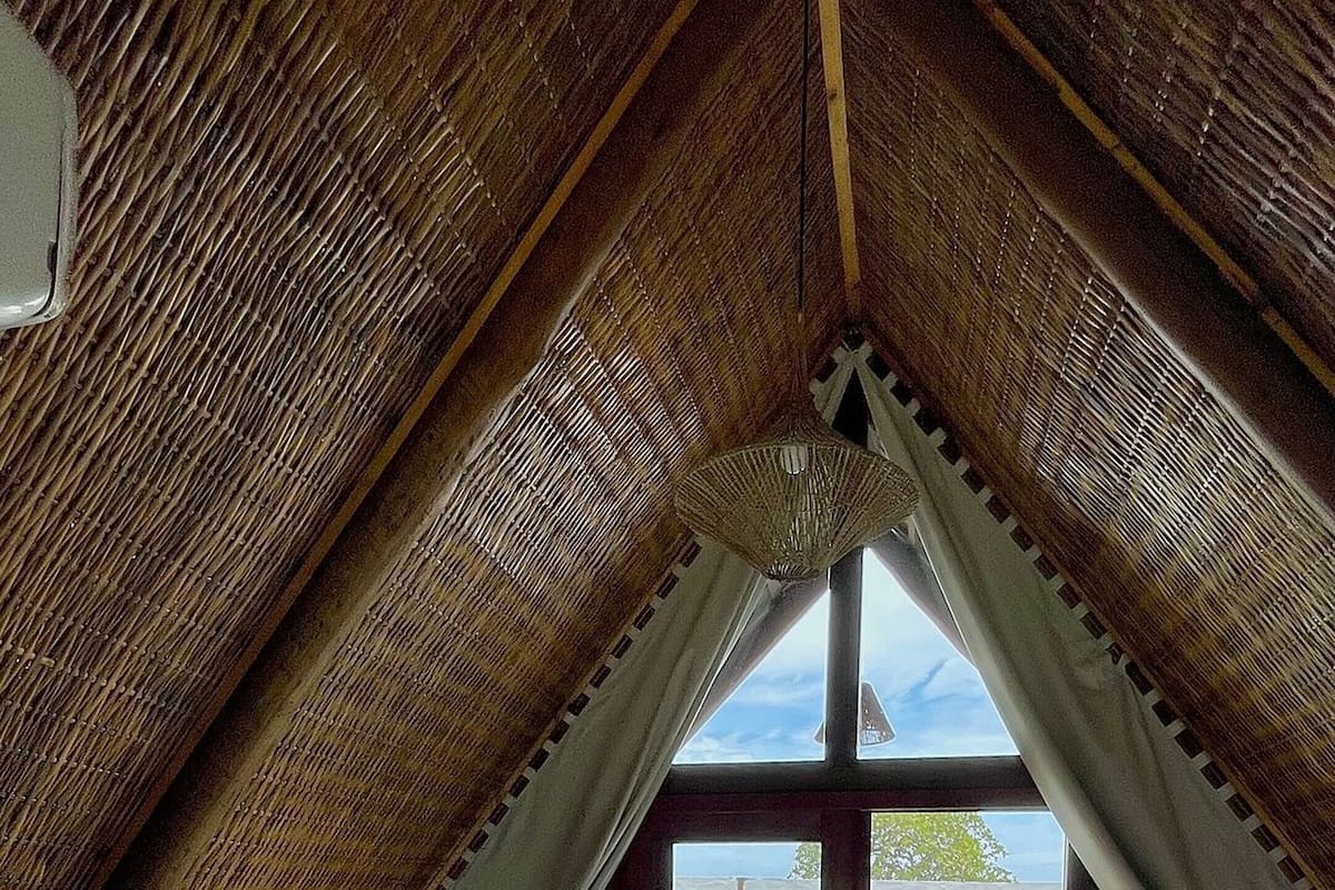 An attic bedroom with a bed, a view of a pool, and a cactus garden outside.