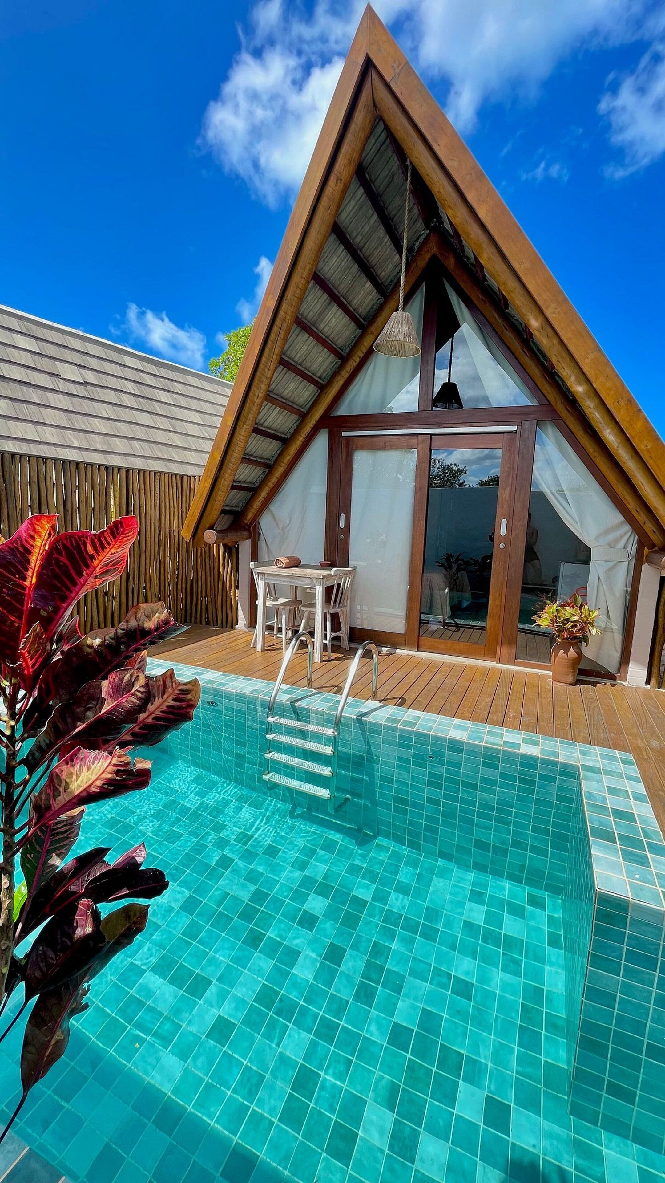 Una casa moderna con techo triangular, piscina y terraza de madera.