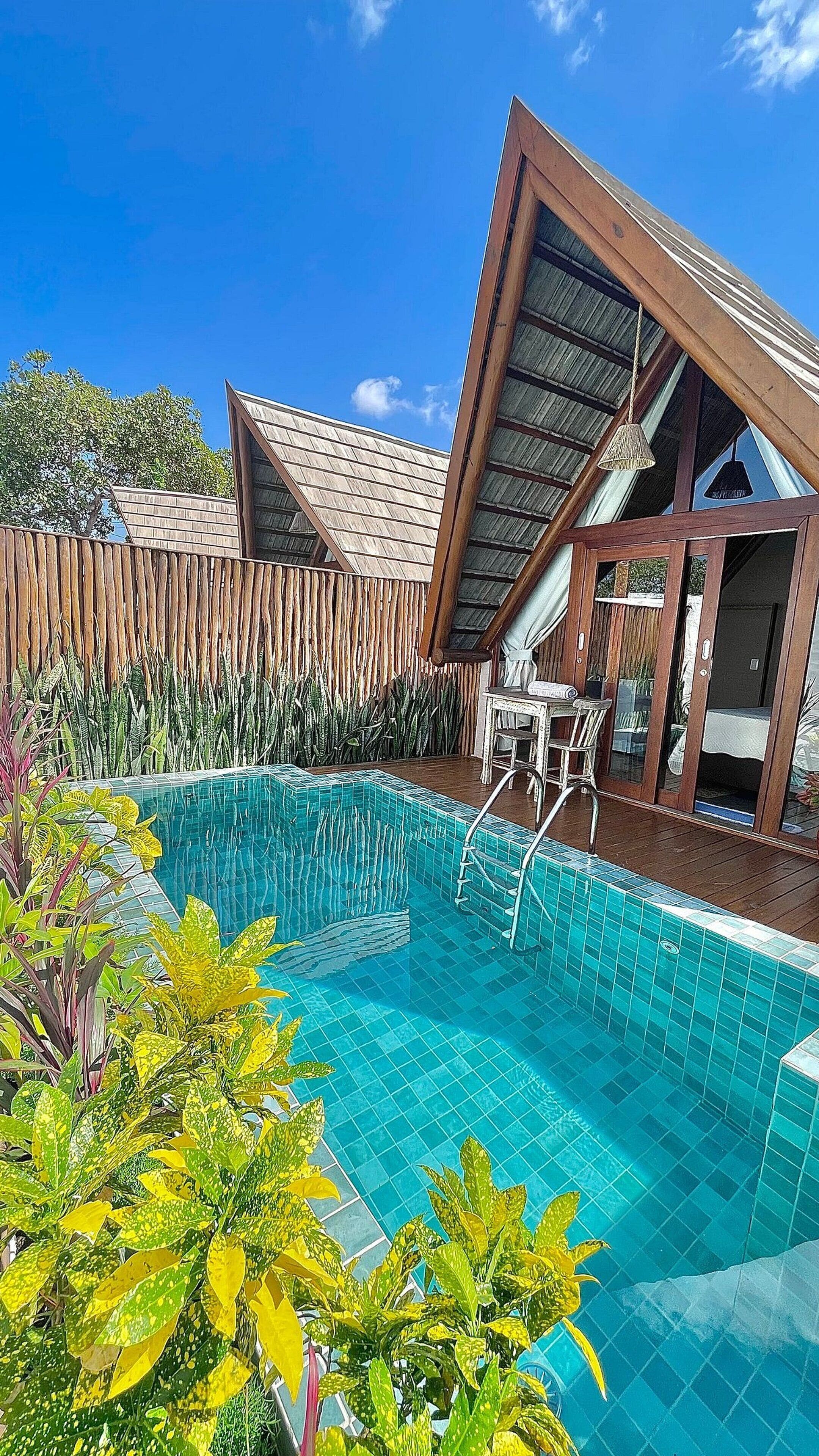 Una piscina con terraza de madera y zona de patio cubierta con cristal.